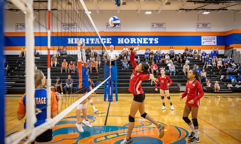 A volleyball player spikes the ball over the net